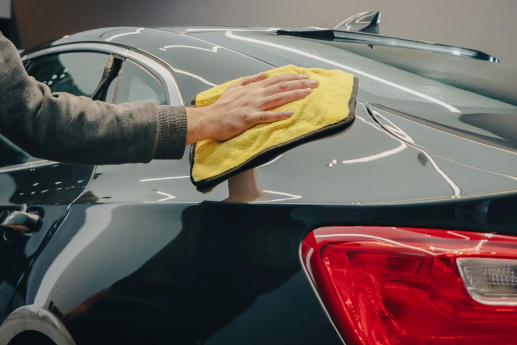 pexels photo 14615260 14615260 Close-up of hand polishing a shiny car with a yellow cloth indoors.