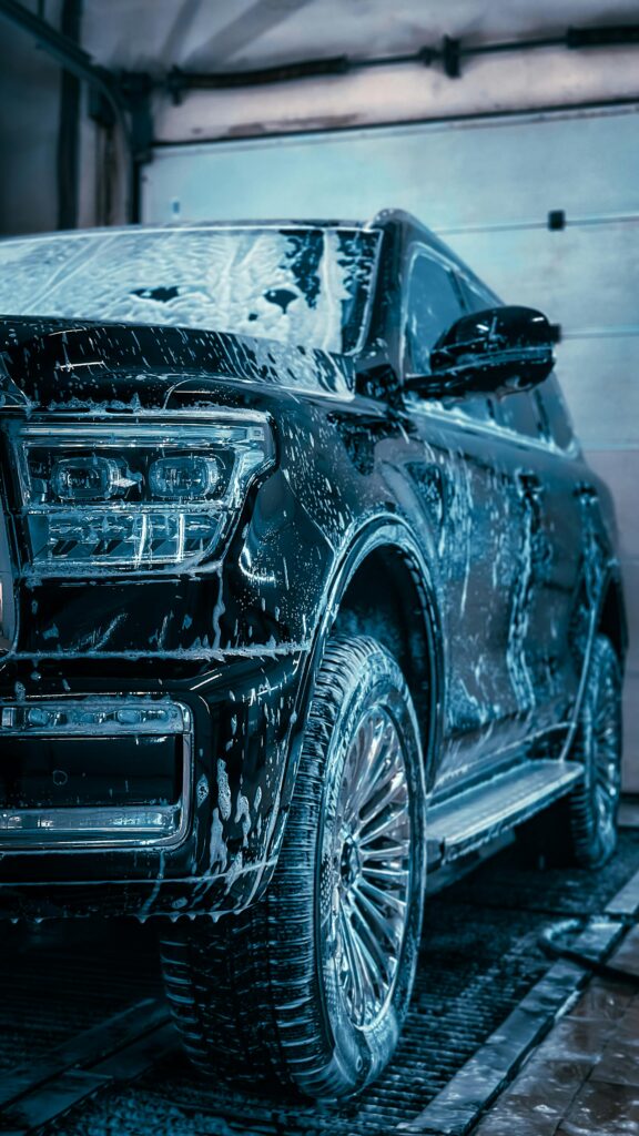 pexels photo 29504457 29504457 Close-up of a sleek SUV covered in soap during a car wash, highlighting cleanliness and care.