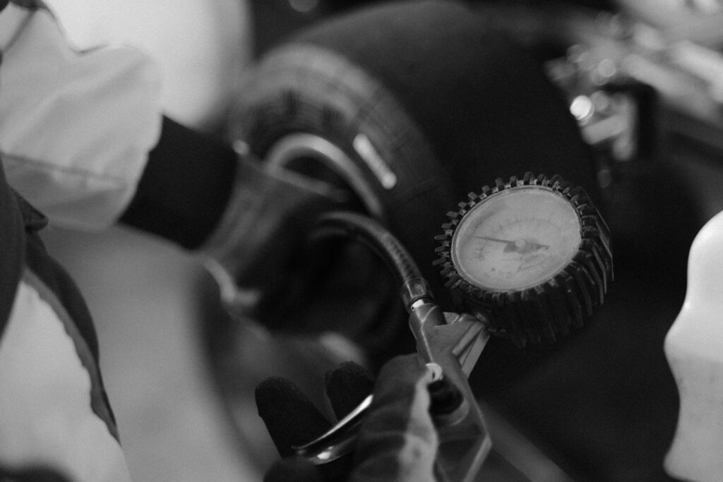 pexels photo 5640643 5640643 Black and white image of a mechanic using a gauge to check tire pressure on a kart wheel.