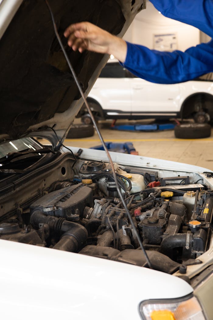 services-03 Close-up of mechanic inspecting car engine under open hood in an auto repair shop.
